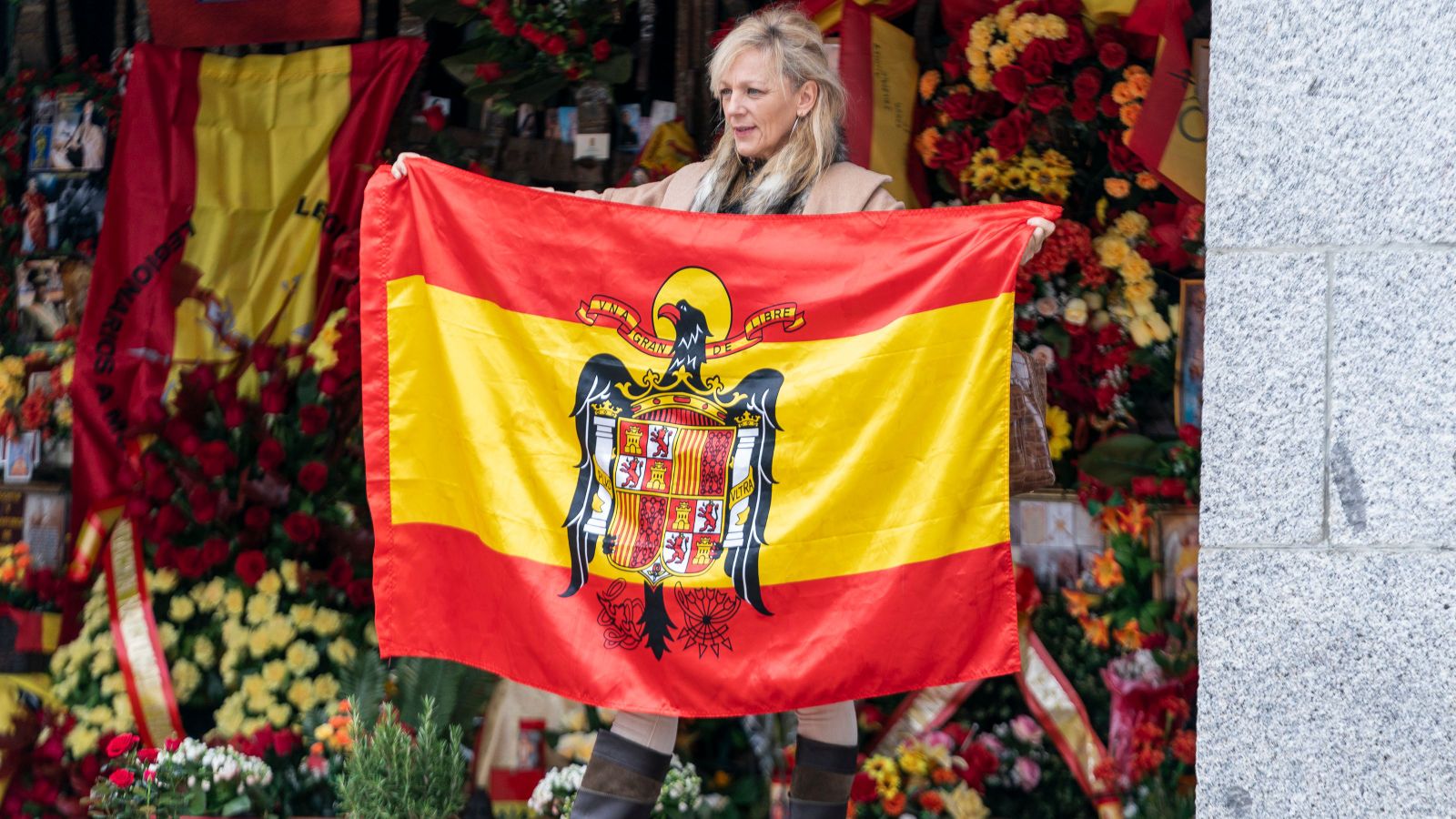 Una dona sosté una bandera amb simbologia franquista davant la tomba de Franco