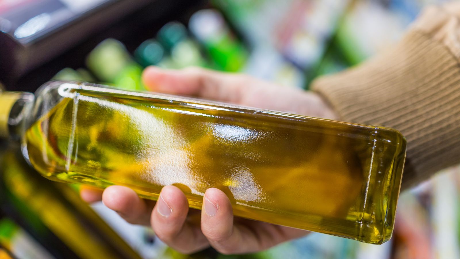 Una persona amb una botella d'oli d'oliva a la mà Una persona amb una botella d'oli d'oliva a la mà