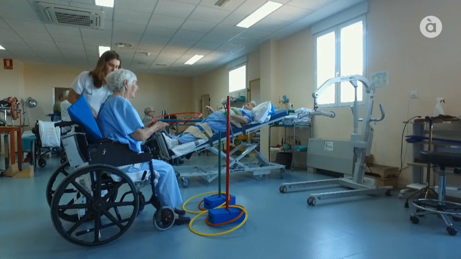 Una pacient fa rehabilitació a l'hospital amb l'ajuda de professionals.