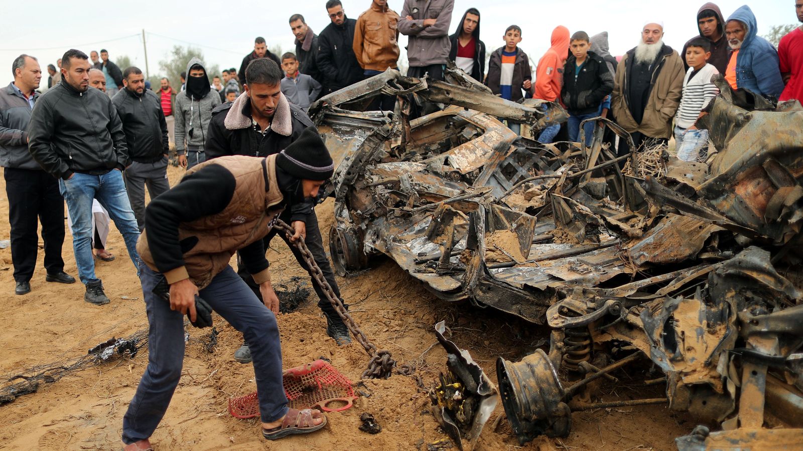 Un grup de palestins observa les restes d’un vehicle destruït per l’atac aeri israelià