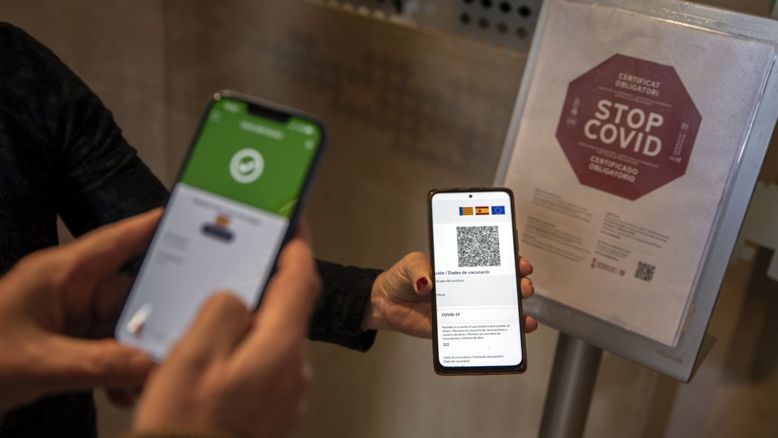 Una clienta mostra el certificat covid a l'entrada d'un establiment hoteler
