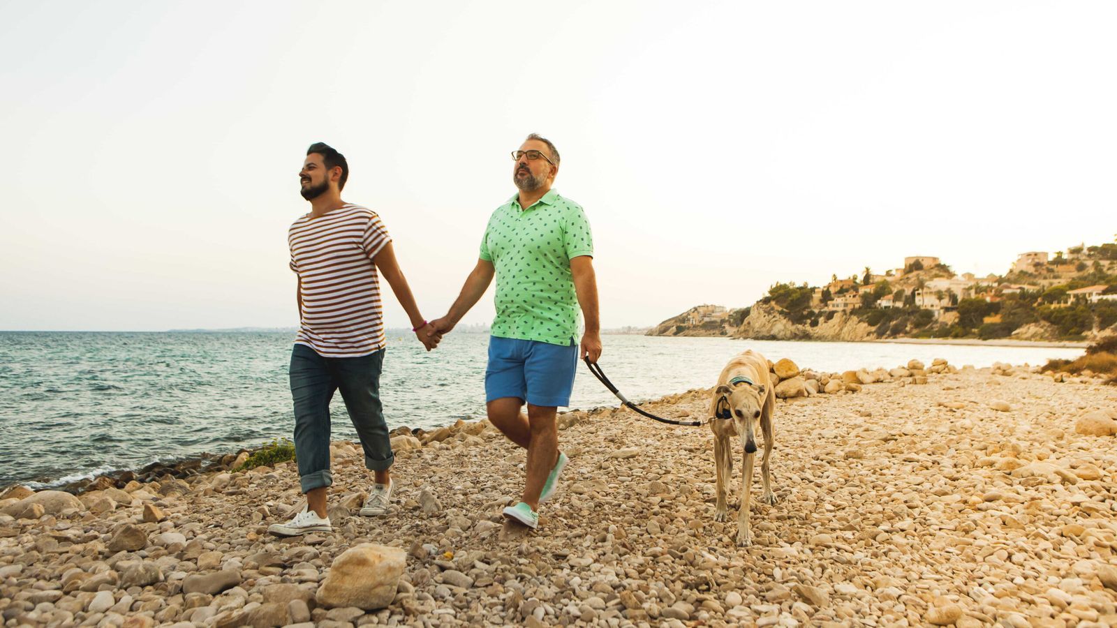Una parella passeja amb el gos per una platja del Campello