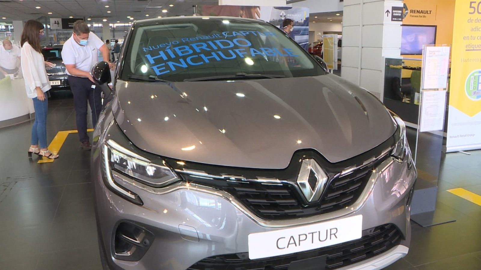 Un venedor mostra a un client el mecanisme per a carregar un cotxe elèctric a un concessionari