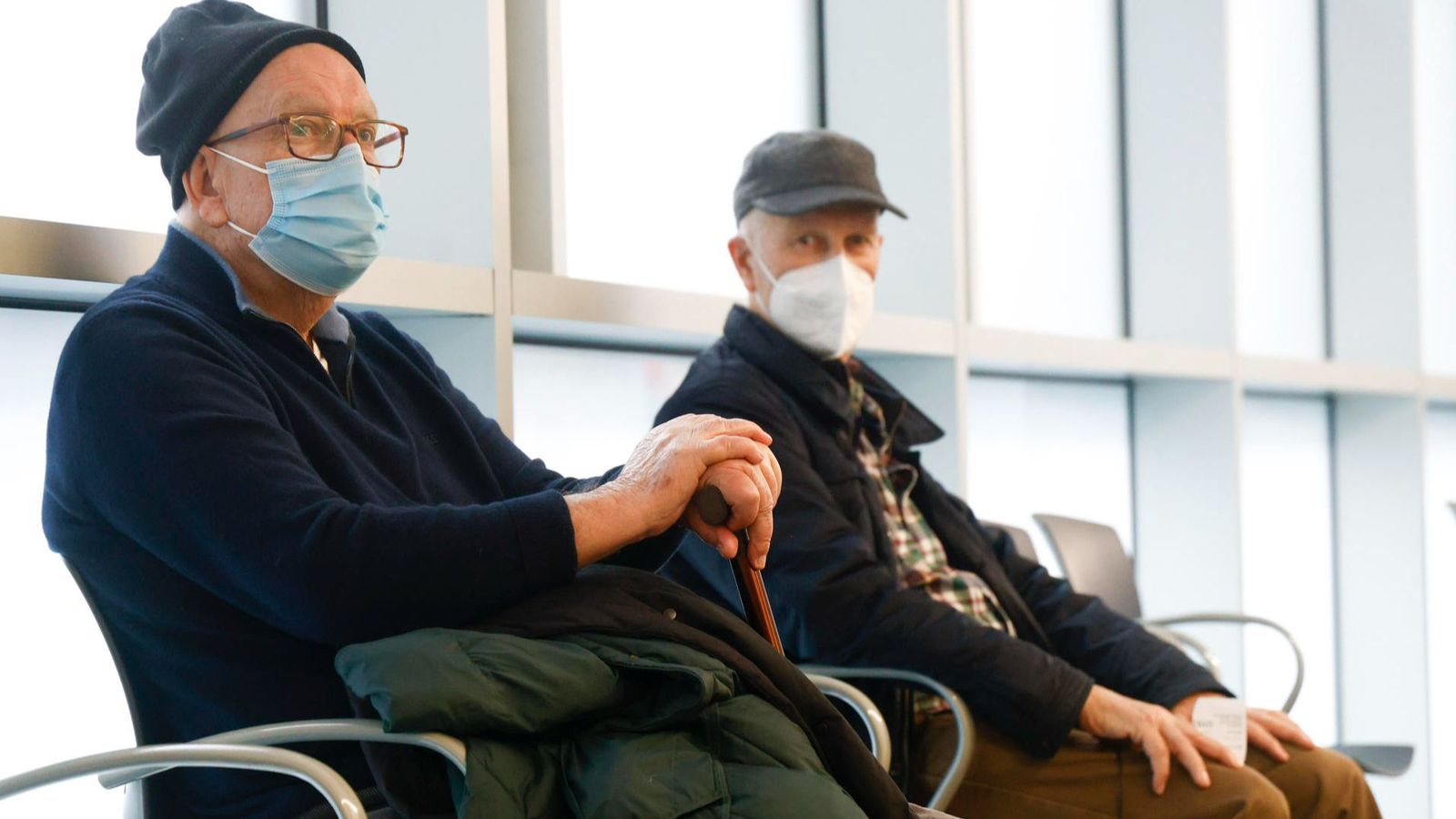 Dos persones majors, amb mascareta, seuen en la sala d'espera d'un centre sanitari
