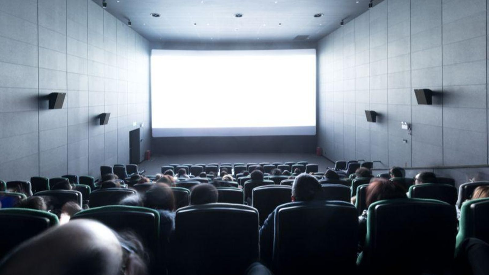 Gent espera que comence una pel·lícula en una sala de cine