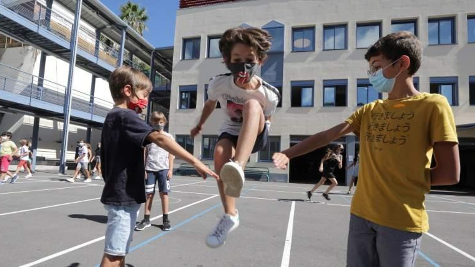 Xiquets jugant al pati del col·legi amb mascaretes