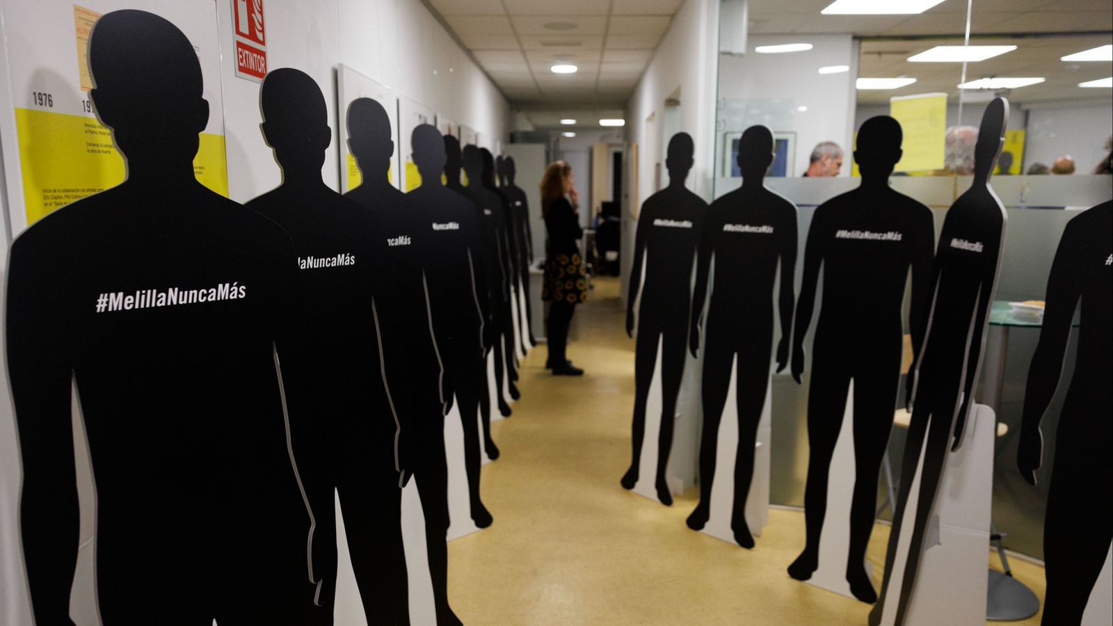 Una integrant d’Amnistia Internacional, en peu, entre les siluetes que representen els migrants morts