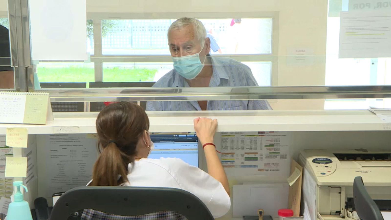 Una treballadora atén un pacient amb mascareta per la finestreta