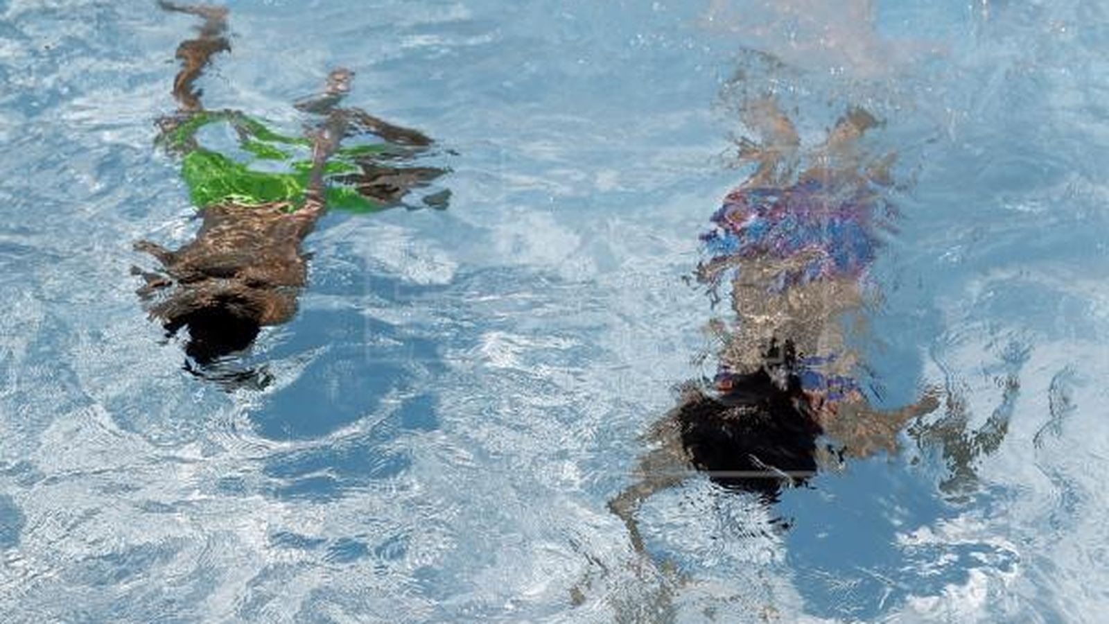 Imatge d'arxiu de dos menors nadant a una piscina