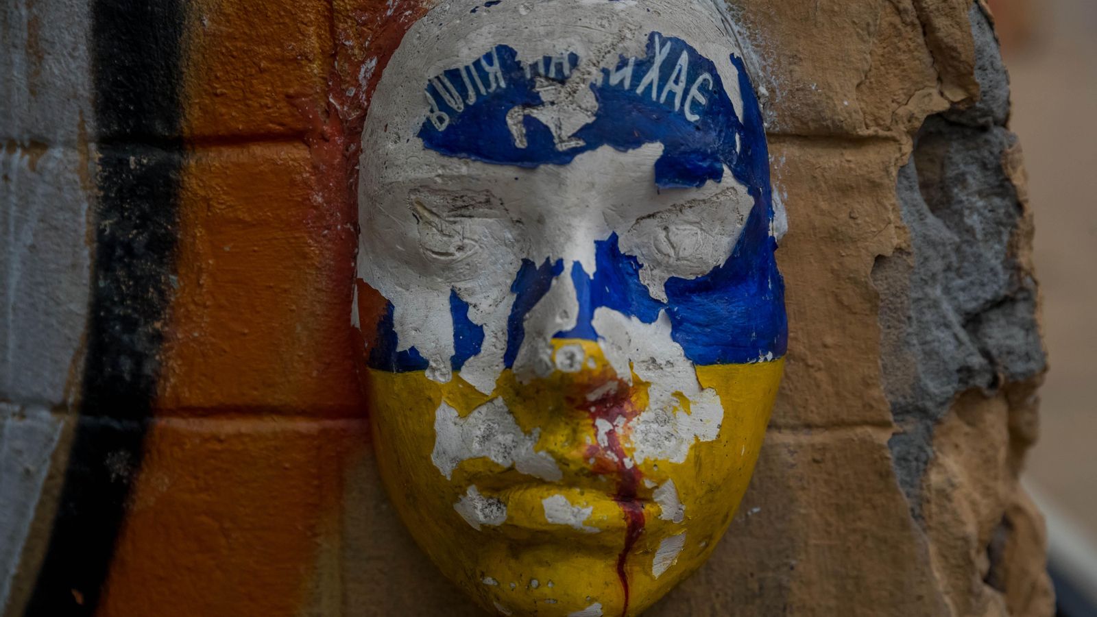 Màscara pintada amb la bandera ucraïnesa, en un mur a Kíev, Ucraïna