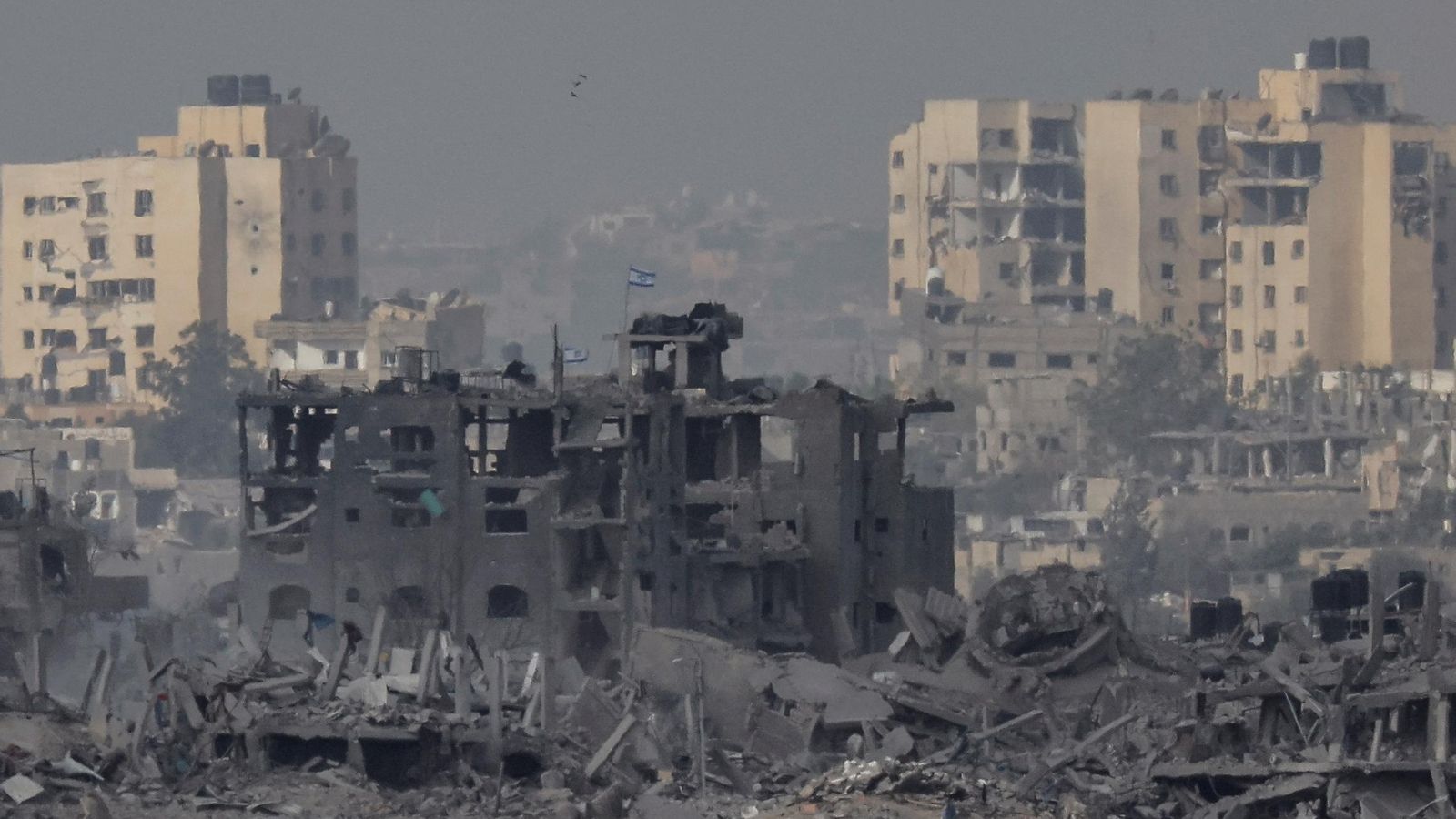 Una bandera israeliana oneja sobre un edifici en runes de la Franja de Gaza