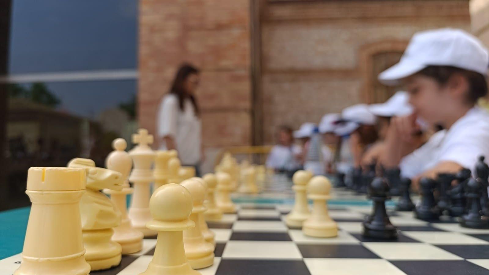 Diversos xiquets i xiquetes juguen una partida d'escacs simultània