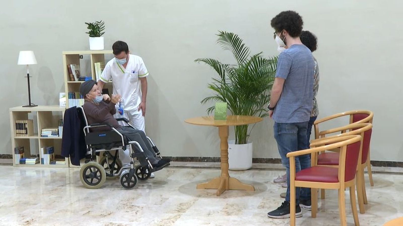 Imatge d'arxiu d'una usuària d'una residència de majors acompanyada per un membre del personal i la seua família