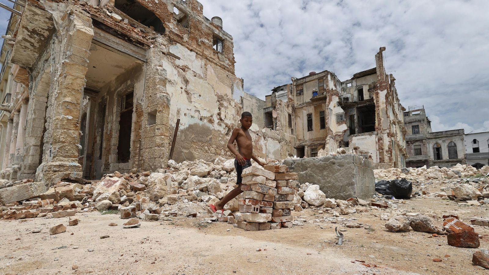Un xiquet carrega rajoles d’un edifici destruït al Malecón de l’Havana este dijous, a l’Havana (Cuba).
