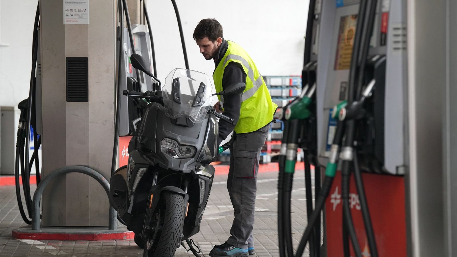 Un empleat ompli el depòsit d'una motocicleta en una gasolinera