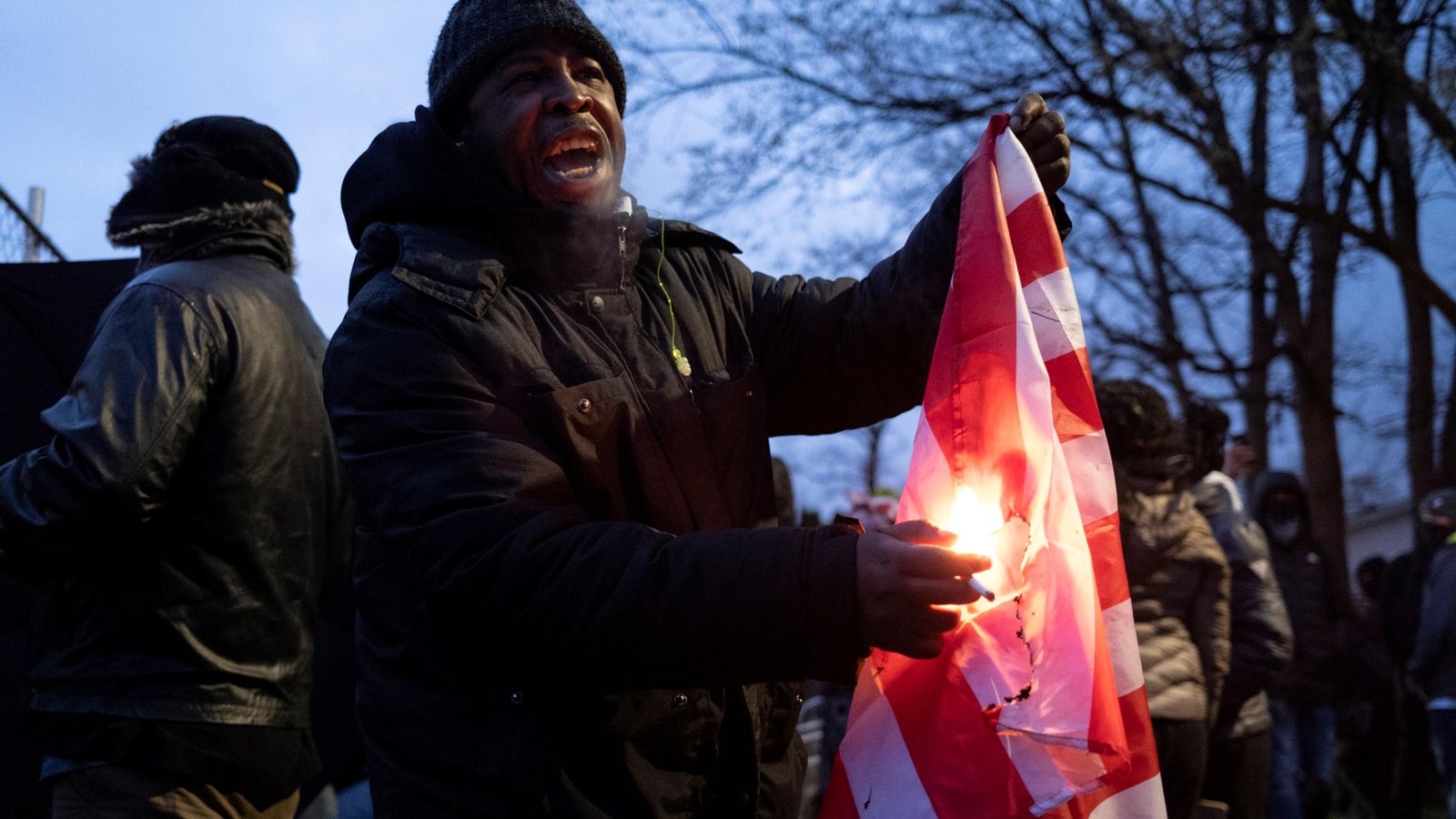 Un home encén una bandera després d'una nit de disturbis a Minnesota, als Estats Units