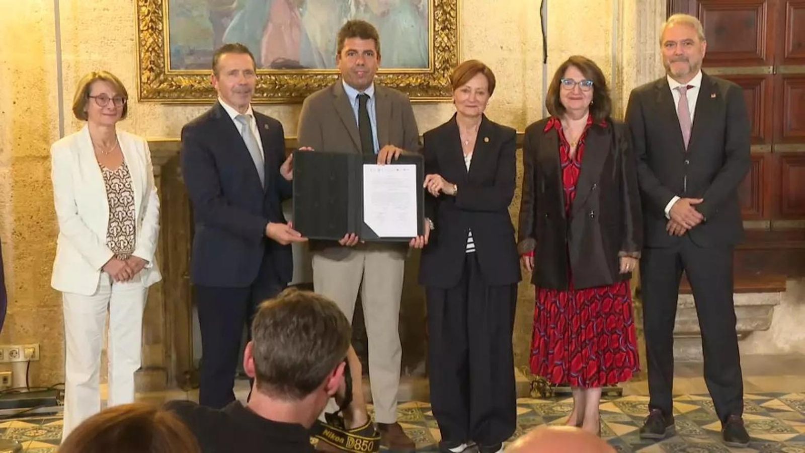 El cap del Consell, al centre, juntament amb els rectors i rectores de les cinc universitats públiques de la Comunitat Valenciana, mostra el document que conté l'acord
