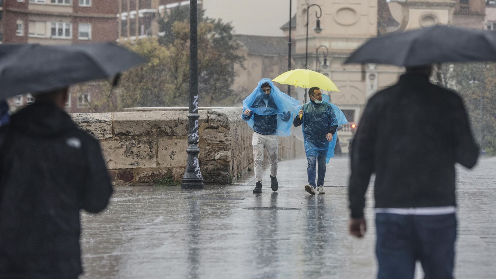 Dues persones amb paraigües i impermeables caminen sota la pluja, el 3 de maig de 2022
