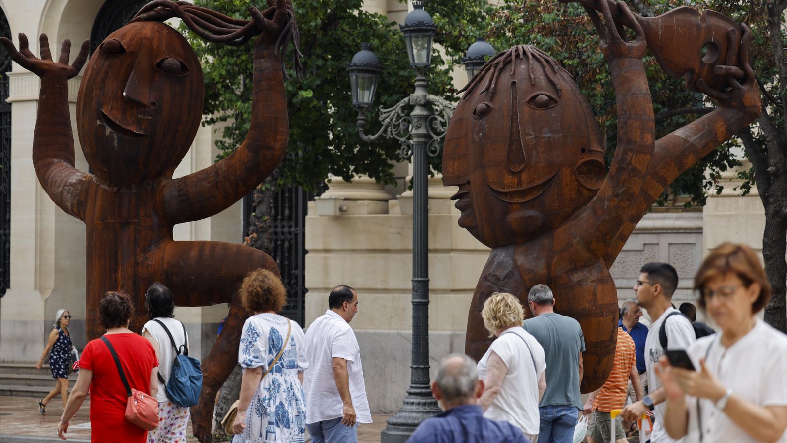 Diverses persones passen al costat de dues escultures de Ripollés en la plaça de l'Ajuntament de València