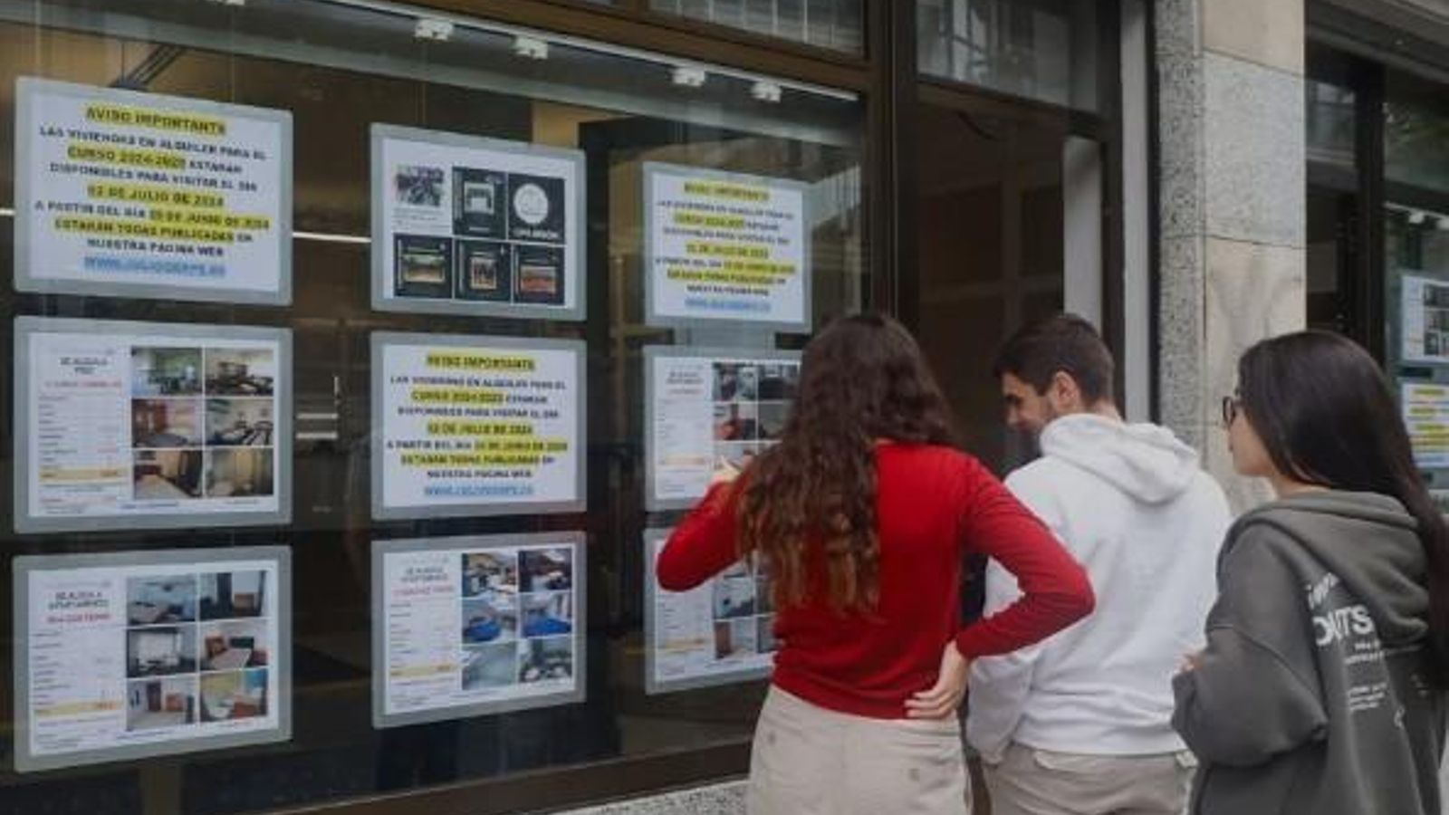 Joves miren anuncis en una immobiliària Joves miren anuncis en una immobiliària