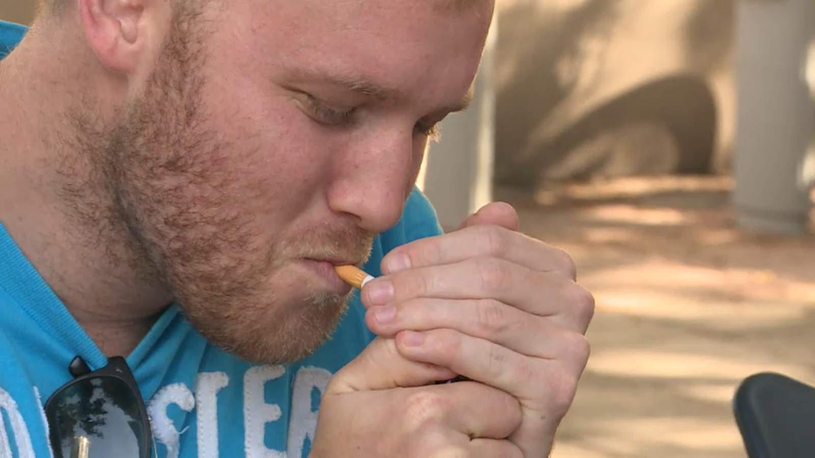 Un jove encén un cigarret a una terrassa