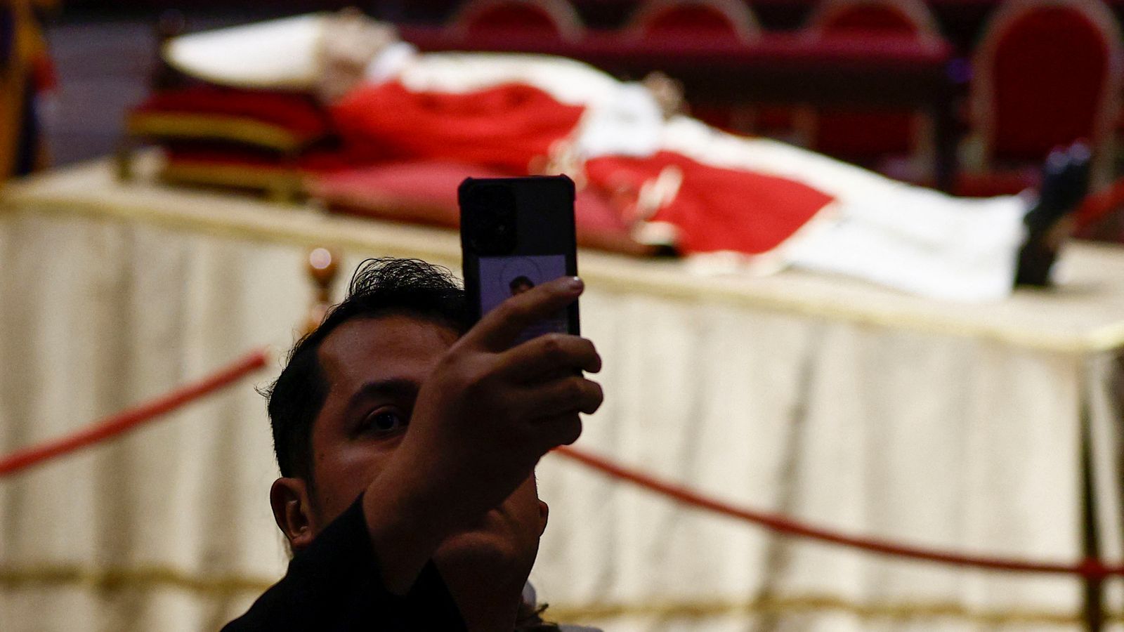 Un visitant es trau una foto amb les restes del papa emèrit de fons