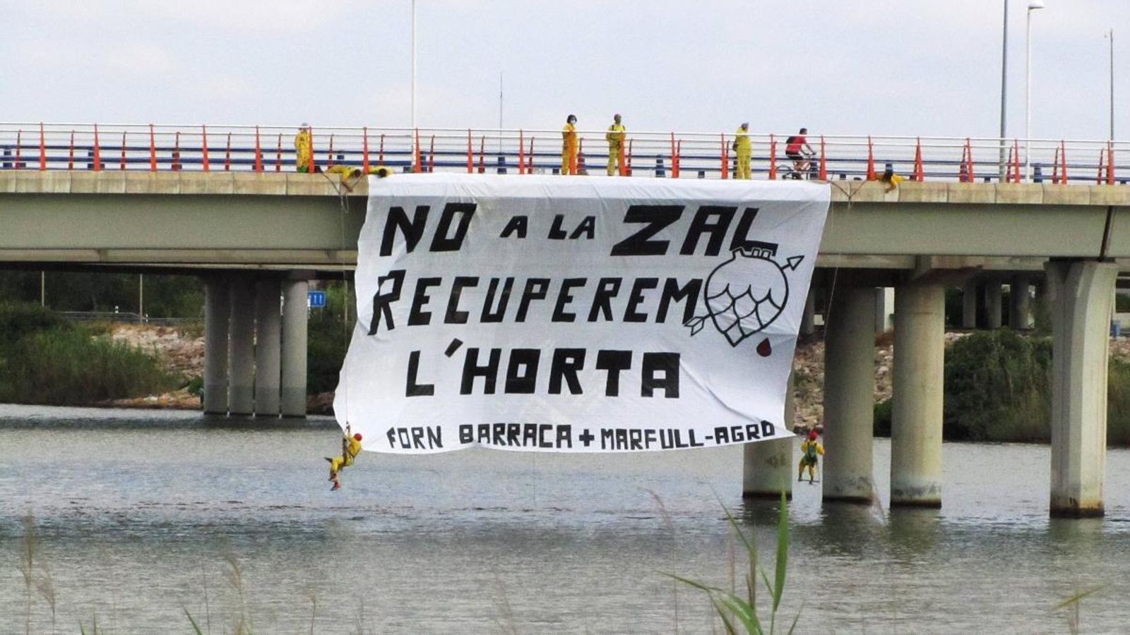 Moment en què els activistes despleguen la pancarta a l'últim pont del riu Túria