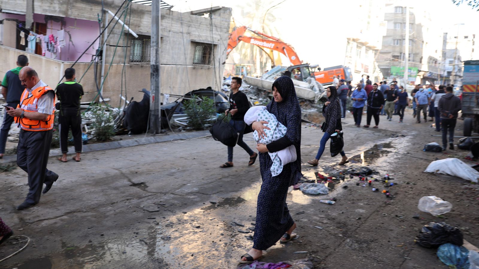 Una dona camina entre les runes que queden després d'un bombardeig israelià amb un nadó als braços