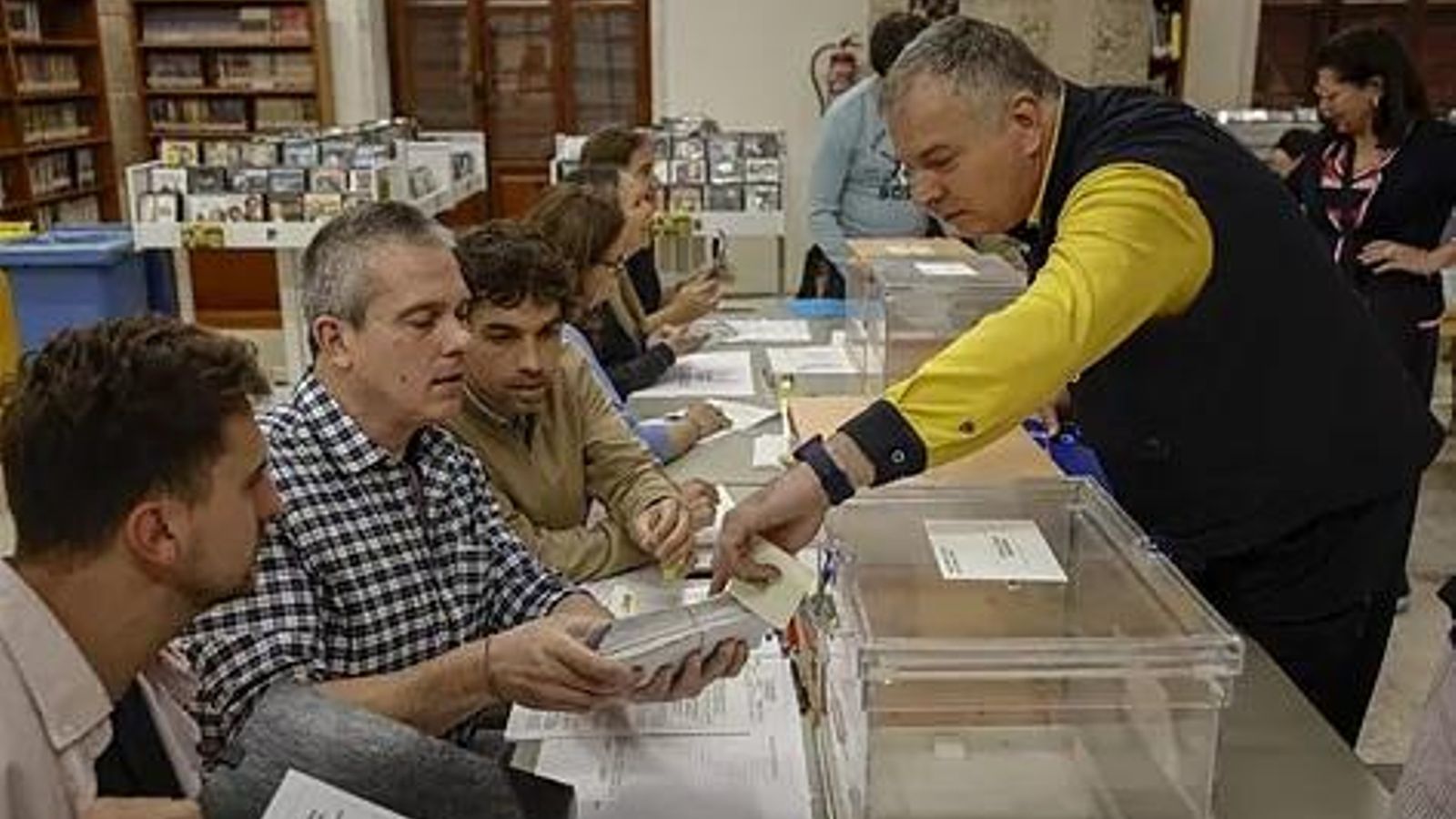 Un carter entrega els vots emesos per correu en una taula electoral
