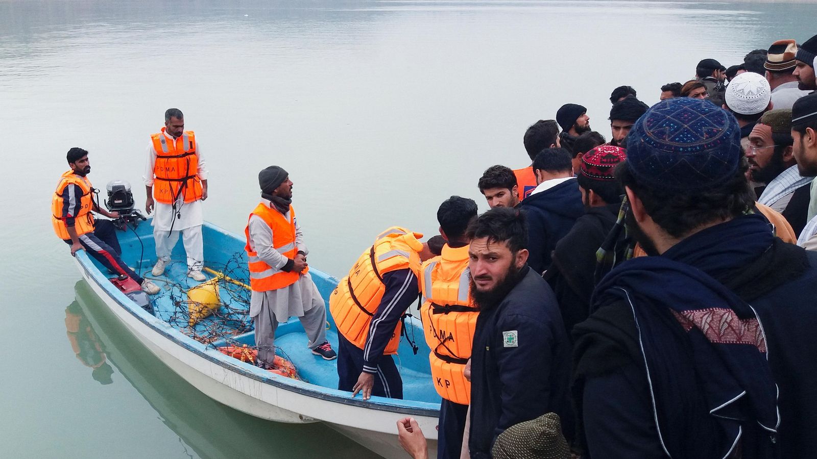 Diverses persones observen els equips de rescat treballar en el llac Tanda a Kohat, Pakistan