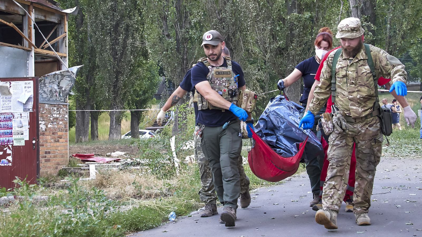 Policies i metges porten el cos d'una dona prop d'un edificidanyat per un atac amb coets russos a Khàrkiv, Ucraïna