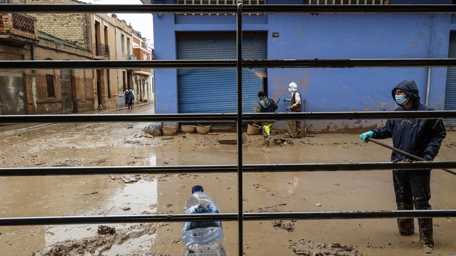 Un home neteja un carrer després dels danys ocasionats per la barrancada a Paiporta