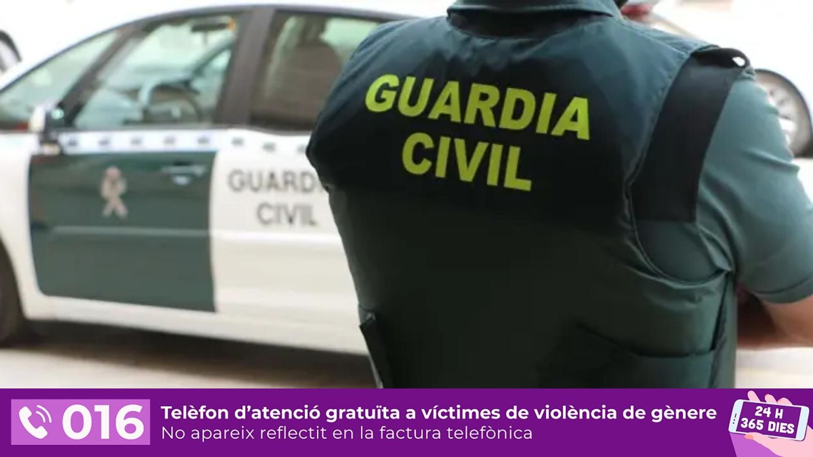 Un agent de la Guàrdia Civil, d'esquena, al costat d'un vehicle oficial
