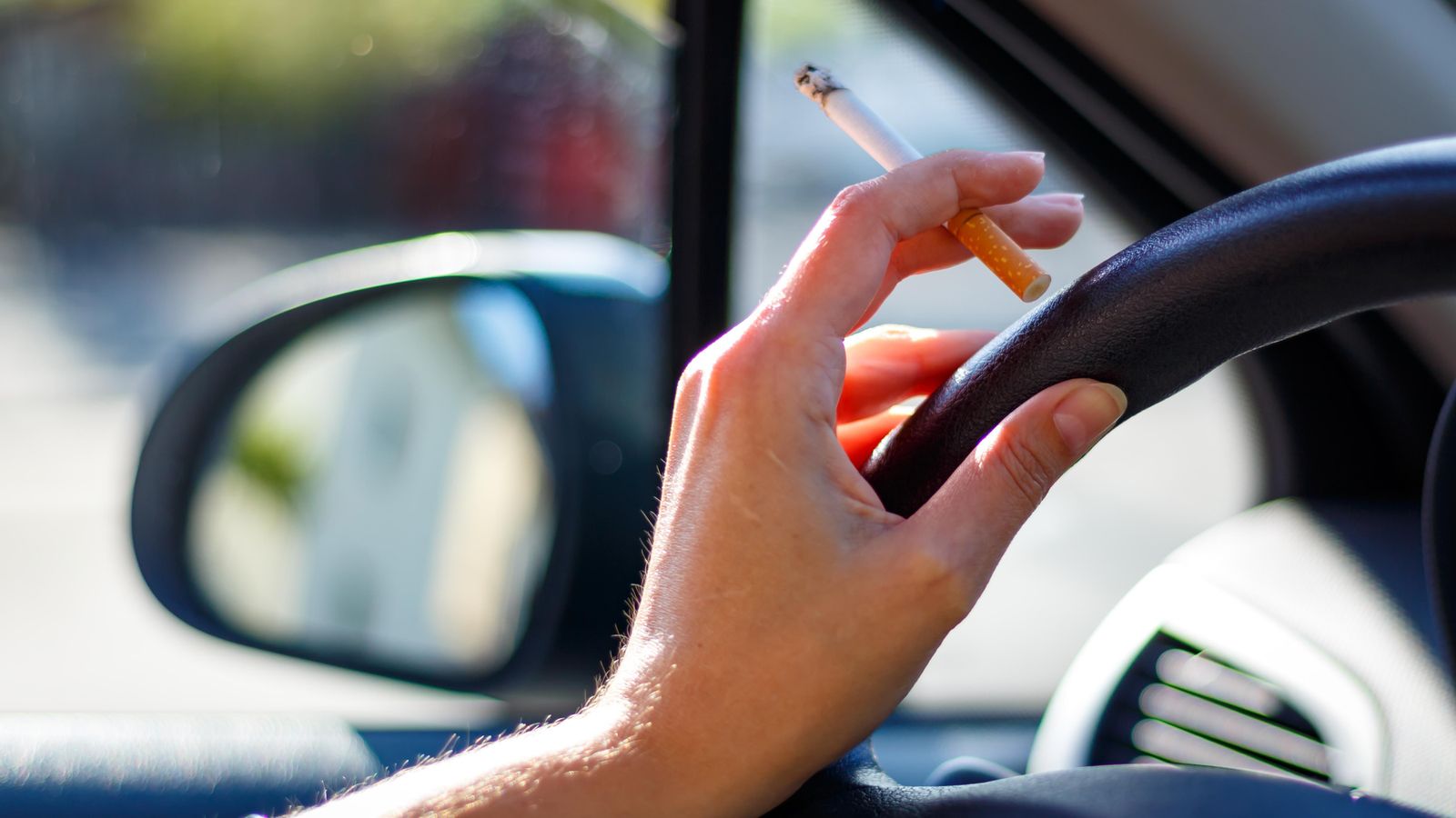 Dona fumant un cigarret al volant d'un cotxe