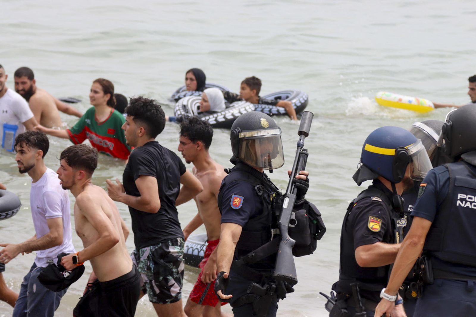 Un dispositiu de la Policia Nacional junt a persones migrants a l'aigua