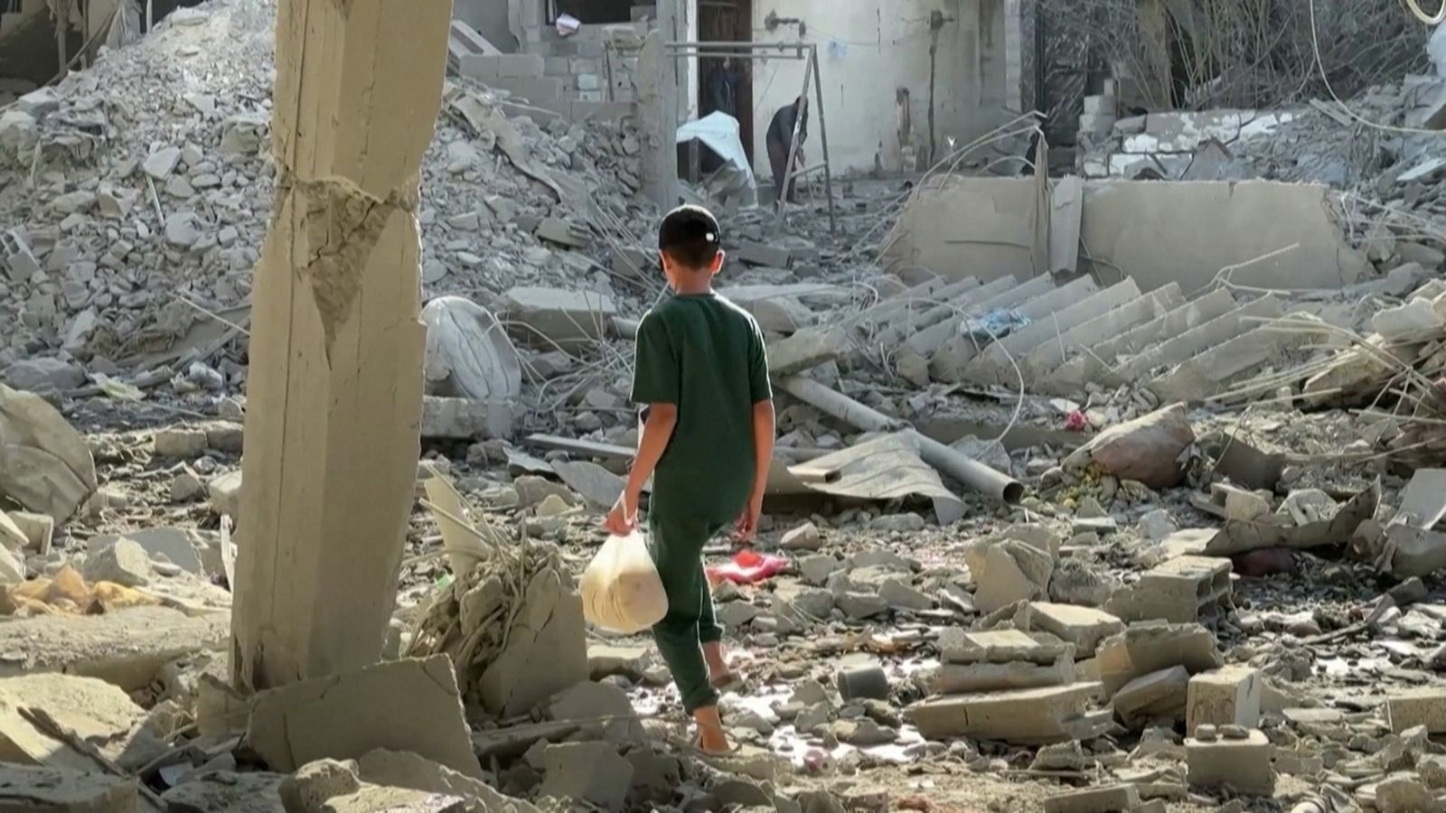 Un xiquet camina entre edificits arrassats pels bombardejos a Gaza