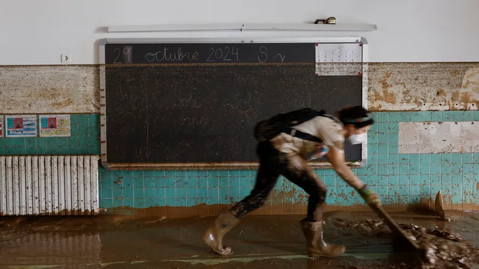 Una dona treballa en les labors de neteja del fang en un col·legi de Sedaví