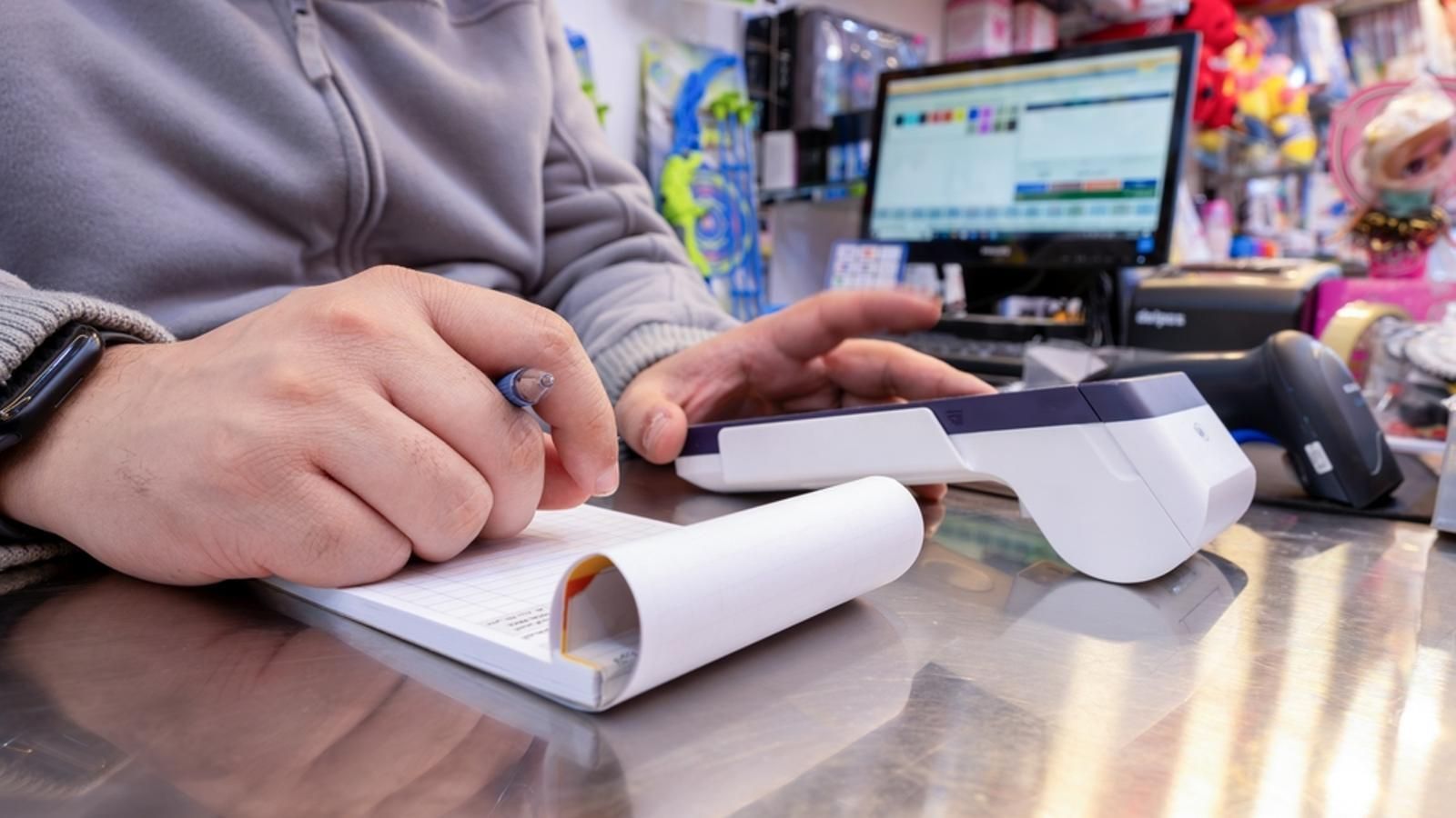 Imatge d'arxiu del propietari d'una botiga revisant les dades d'un datàfon