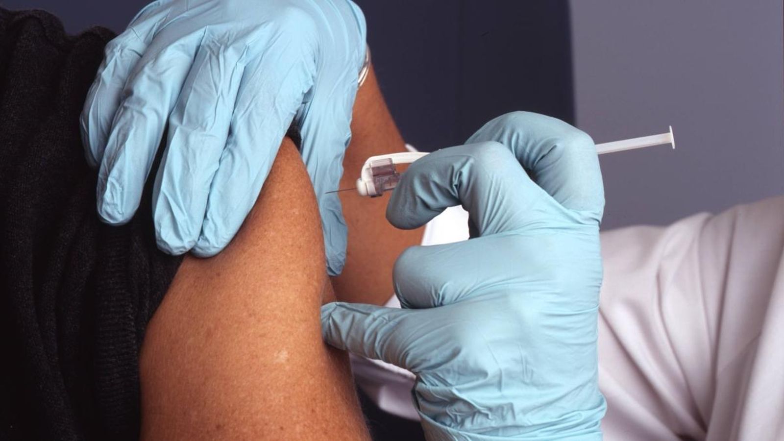 Un sanitari injecta una vacuna a un pacient, en una imatge d'arxiu
