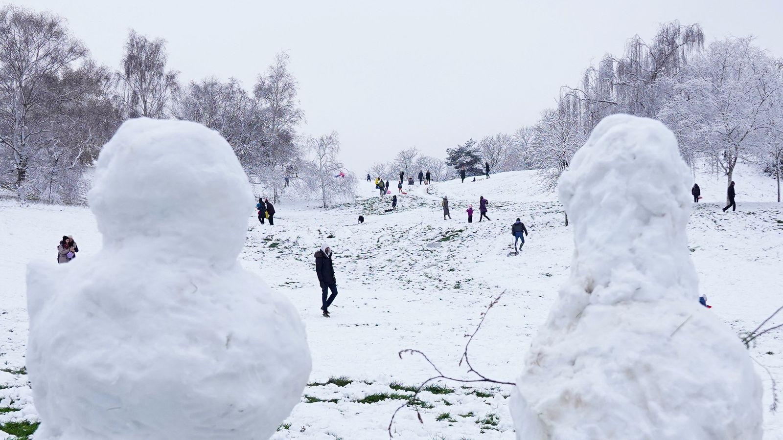 Diverses persones caminen pel parc Greenwich, cobert de neu, a Londres