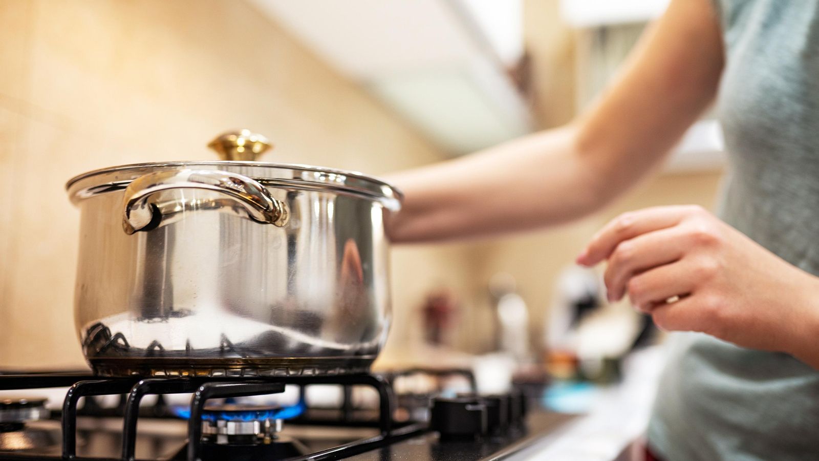Una dona encén el foc a gas, a la cuina