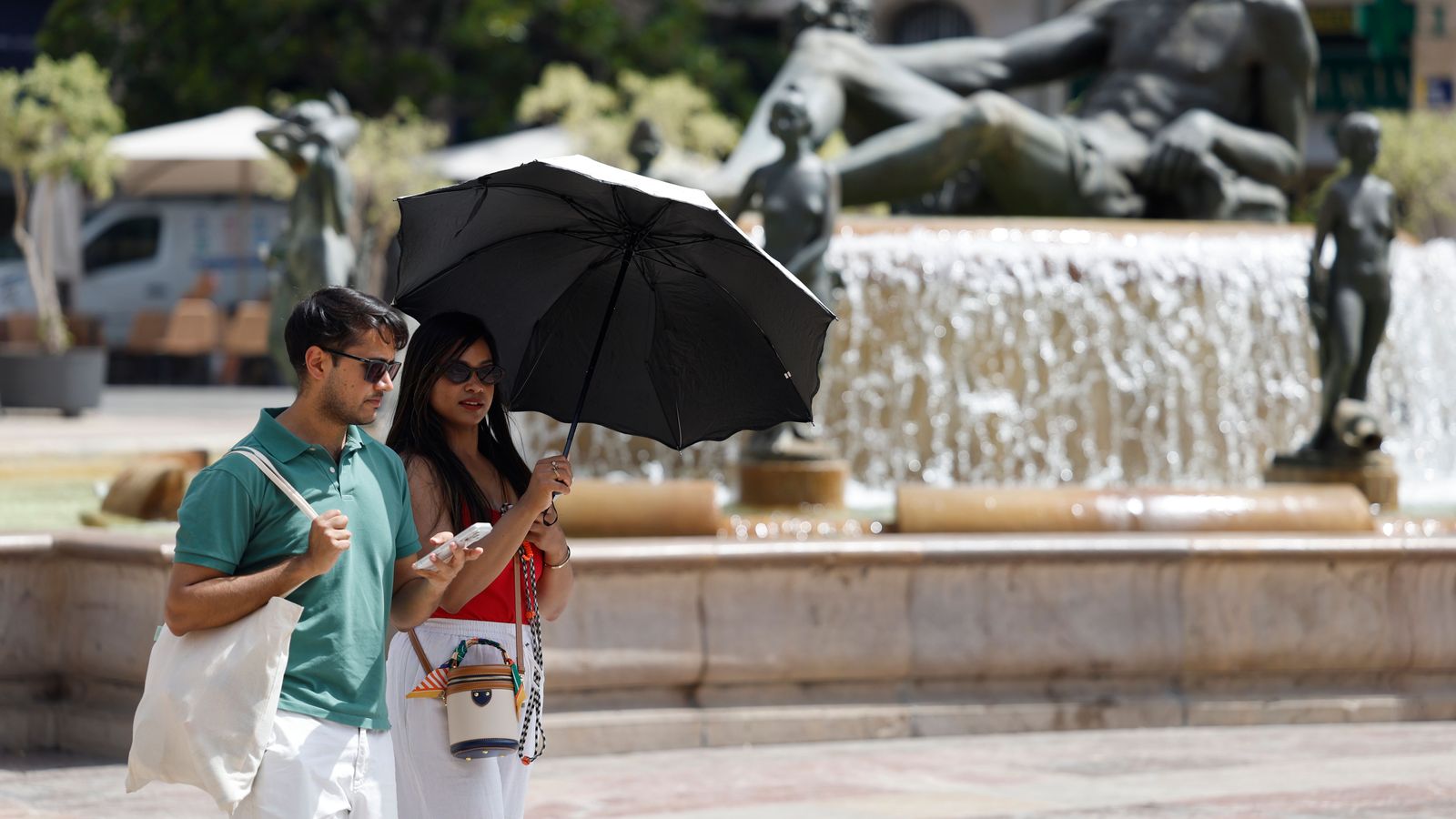 Dos turistes es protegixen de la calor a la plaça de la Mare de Déu de València