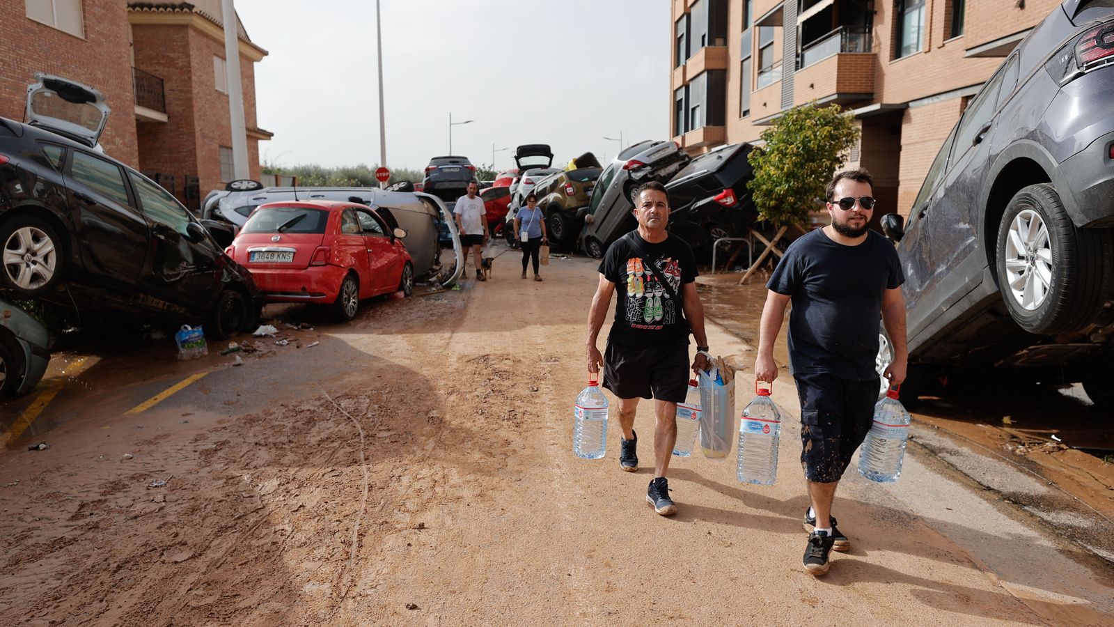 Un grup de veïns trasllada aigua per un carrer de Paiporta