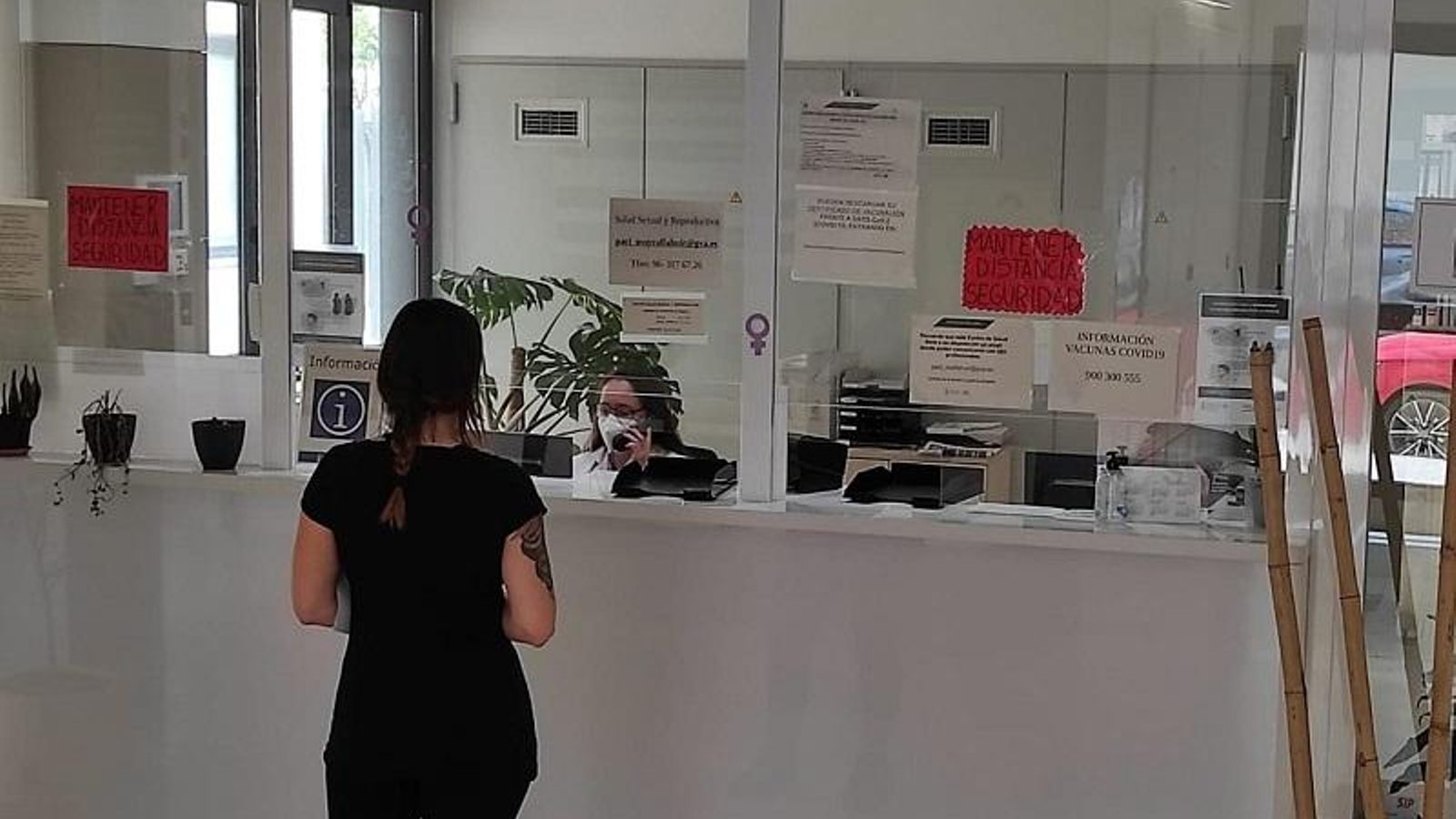 Una dona demana cita en un mostrador d'un centre de salut