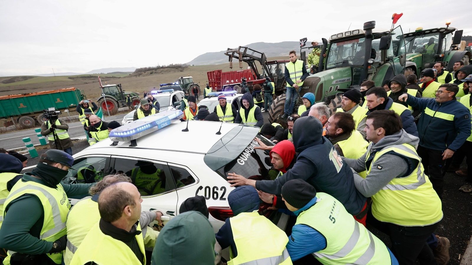 Un grup de llauradors envolta un cotxe de la Guàrdia Civil l'accés a Pamplona, aquest dijous