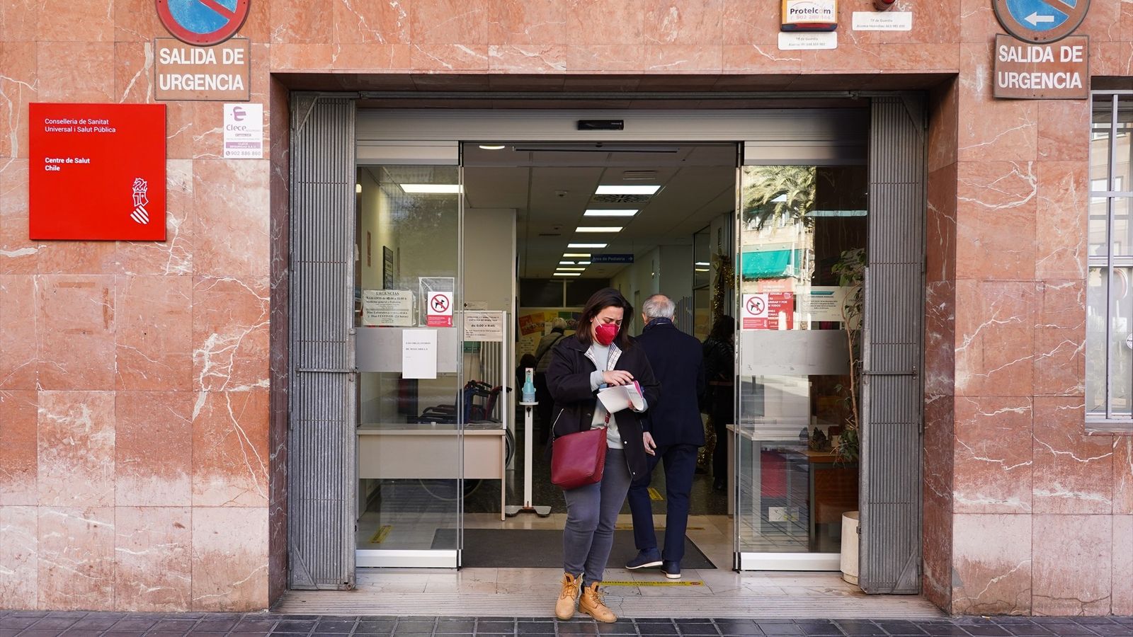 Una dona amb mascareta ix per la porta d'un centre de salut