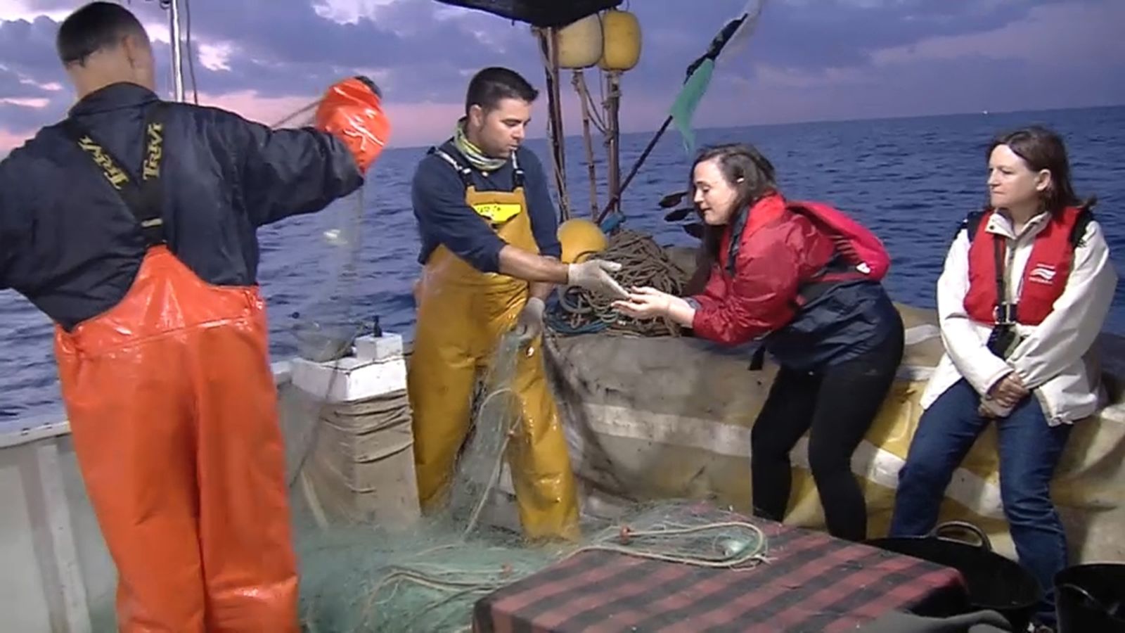 Uns pescadors mostren a unes turistes com fan les seues tasques