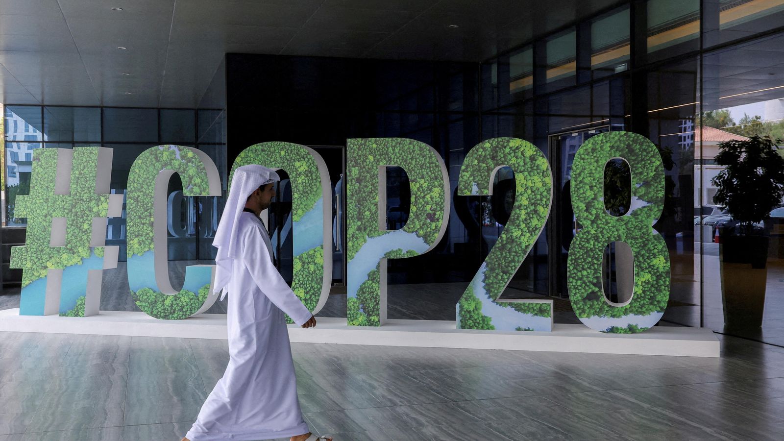 Una persona passa per davant d'un cartell promocional de la COP28 a Dubai