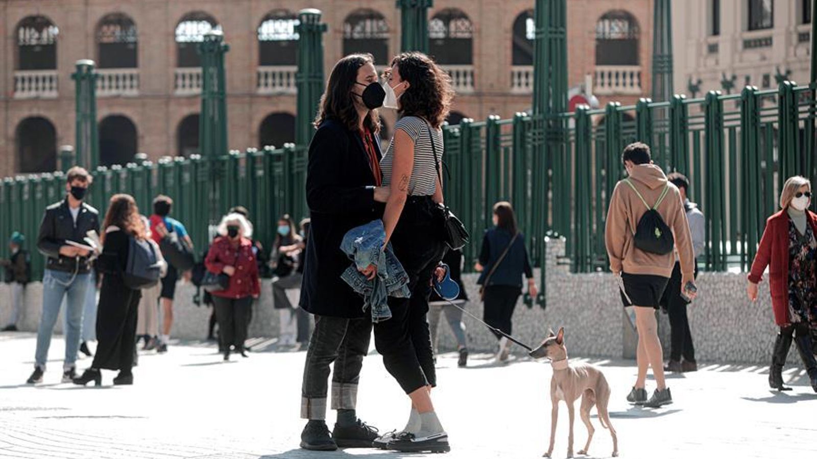 Una parella es besa, protegida per les mascaretes, davant de l'Estació del Nord de València