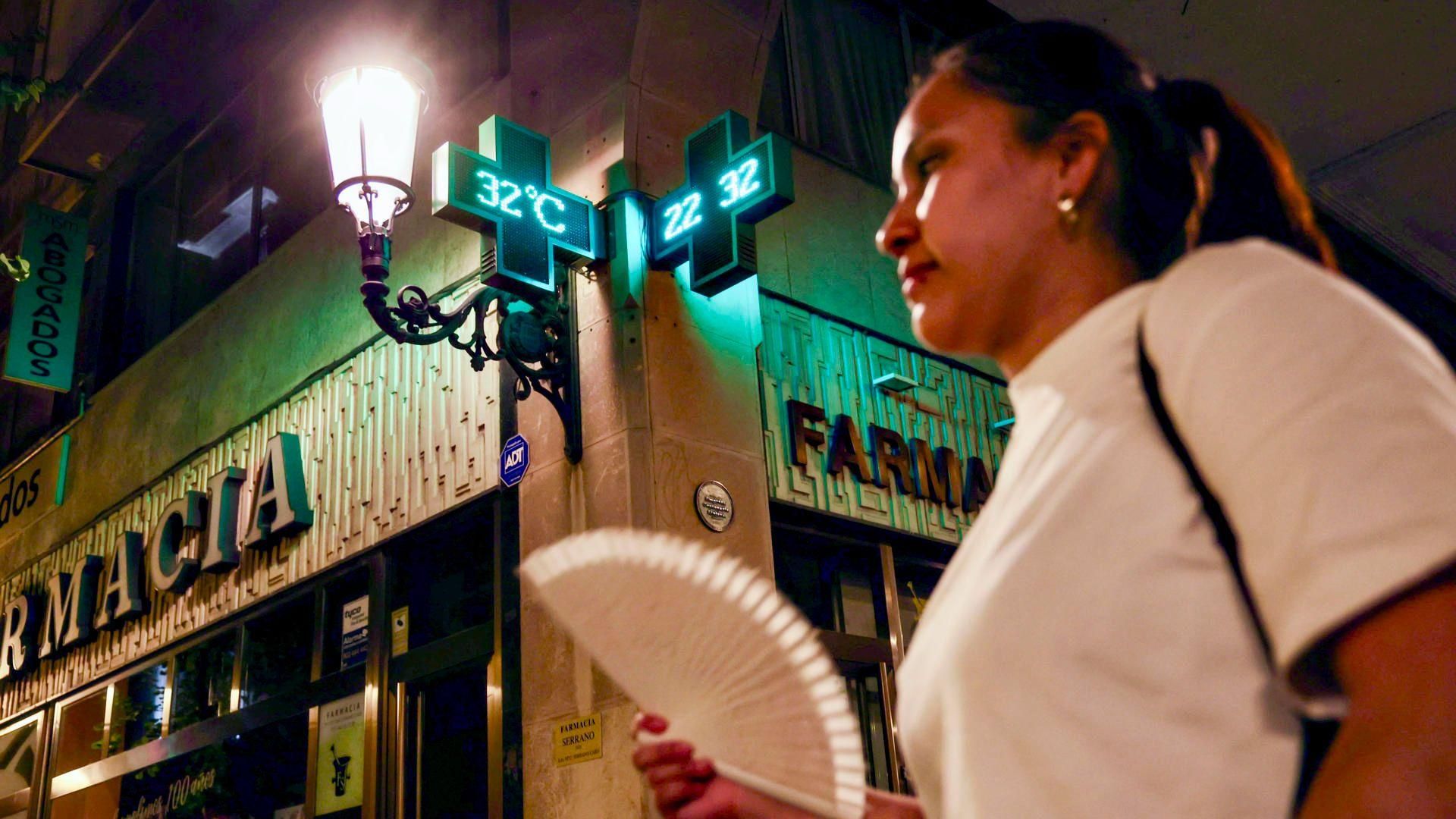 Una dona es venta en un carrer de nit, amb 32 °C al termòmetre Una dona es venta en un carrer de nit, amb 32 °C al termòmetre